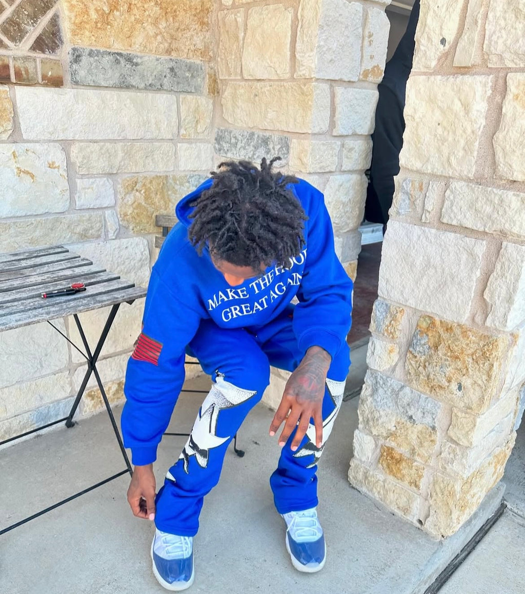 youtuber lil loaded wearing a blue hoodie with the text 'MAKE THE HOOD GREAT AGAIN' on it,  paired with matching blue pants with a graphic design, standing outdoors. from neighborhood supplier