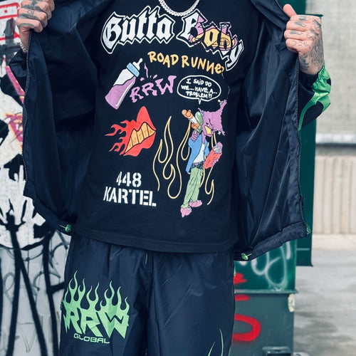 A person holding a black t-shirt with 'GUTTA BABY' and 'ROADRUNNER' text and graphics. neighborhood supplier rrw x gutta baby streetwear tee